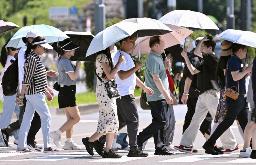 　真夏のような強い日差しの下、日傘を差す人たち＝６月２８日、東京都千代田区