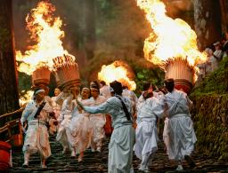　熊野那智大社で開かれた例大祭「那智の扇祭り」。白装束の氏子らが燃えさかる大たいまつを担ぎ練り歩いた＝１４日午後、和歌山県那智勝浦町