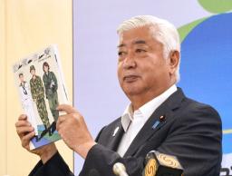 　２０２５年版防衛白書を掲げる中谷防衛相＝１５日午前、防衛省