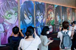 　「鬼滅の刃」の最新映画が公開初日を迎え、キャラクターのパネルを撮影する観客ら＝１８日午前、東京都千代田区の「ＴＯＨＯシネマズ日比谷」