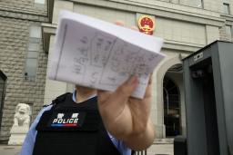 　スパイ罪で起訴された日本人男性の判決公判が開かれた北京市の第２中級人民法院前で撮影を阻止する警察官＝１６日（共同）