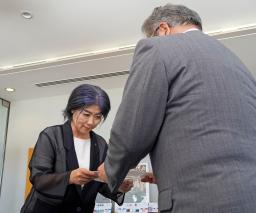 　静岡県伊東市議会の中島弘道議長（右）から証人尋問に出席するよう求める文書を受け取る田久保真紀市長＝２２日午前、伊東市役所