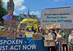 　国際司法裁判所が入る「平和宮」前で、気候変動への対応を訴え気勢を上げるデモ参加者＝２３日、オランダ・ハーグ（共同）