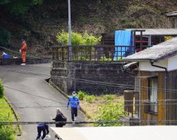 　強盗殺人事件の現場となった民家（右奥）の周辺を調べる捜査員＝２７日午前、佐賀県伊万里市