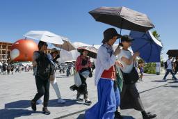 　大阪・関西万博の会場で、日傘を差して歩く人たち＝２６日、大阪市此花区の夢洲
