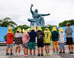 　平和公園を訪れ、平和祈念像の前で手を合わせる園児たち＝８日午後、長崎市