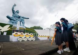 　長崎市の平和公園を訪れ、平和祈念像の前で手を合わせる女の子ら＝９日午後