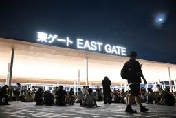 　大阪メトロ中央線が運転見合わせとなり、万博会場で座り込む人たち＝１３日午後１１時２分、大阪市此花区の夢洲