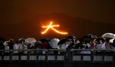 　京都の伝統行事「五山送り火」が行われ、夜空に浮かび上がった文字を見る人たち＝１６日夜、京都市