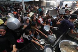 　ガザ中部ヌセイラト難民キャンプで、配給の食べ物を受け取ろうとする人たち＝１６日（ゲッティ＝共同）