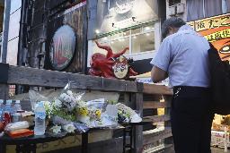 　大阪・道頓堀のビル火災で、現場付近に設置された献花台に花を供え手を合わせる男性＝１９日