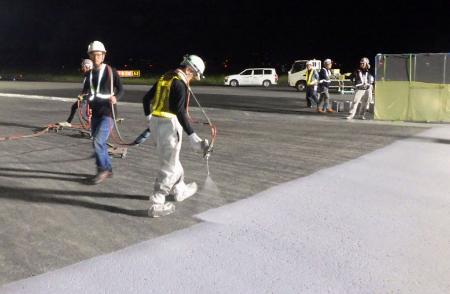 　滑走路の誘導路を舗装する作業員＝７日未明、成田空港（ＮＡＡ提供）