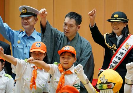 　警視庁神田署の交通安全啓発イベントで腕を振り上げる、講談師の神田伯山さん（後列中央）と高橋建次署長（同左）ら＝７日午後、東京都千代田区