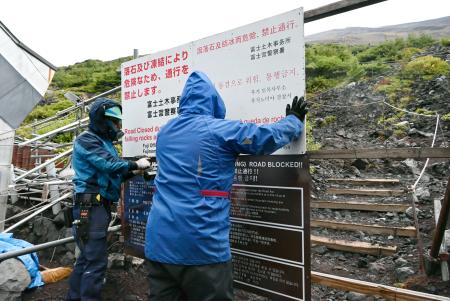 　富士山の登山道を冬季閉鎖するため、看板を設置する作業員＝１０日午後、静岡県富士宮市