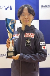 　トロフィーを手に撮影に応じるフィギュアスケート男子の鍵山優真＝１６日、羽田空港