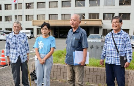 　佐賀県警本部前で取材に応じる日本国民救援会佐賀県本部の山口勝弘事務局長（右から２人目）＝２４日午後