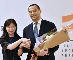 　退任に当たり、職員から花束を受け取るスポーツ庁の室伏広治長官（右）＝３０日午後、東京・霞が関