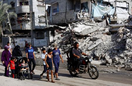 　４日、ガザ中部で、イスラエルによって破壊された建物のそばを歩く人々（ロイター＝共同）
