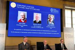 　ノーベル物理学賞を（スクリーン左から）ジョン・クラーク氏、ミシェル・デボレ氏、ジョン・マルティニス氏に授与すると発表した記者会見＝７日、ストックホルム（共同）