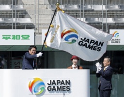 　「わたＳＨＩＧＡ輝く国スポ」の総合閉会式で、滋賀県の三日月大造知事（右）から引き継いだ大会旗を振る次回開催地青森県の宮下宗一郎知事＝８日、平和堂ＨＡＴＯスタジアム