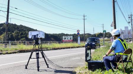 　事故現場付近で速度違反車を監視する警察官＝９日午前、三重県名張市