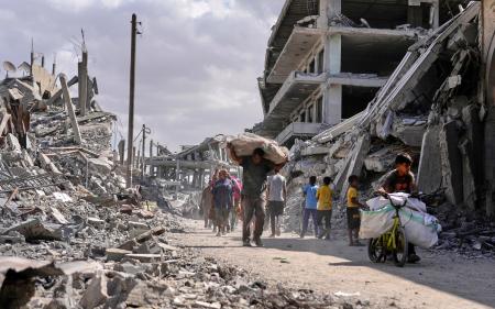 　ガザ南部ハンユニスで荷物を持って歩く人たち。イスラエルとイスラム組織ハマスの停戦が発効した＝１０日（ＡＰ＝共同）