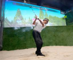 　富士通が設置した、ゴルファーのスイングをＡＩで分析、上達に向けたアドバイスをする技術のブースでバンカーショットを放つ来場者＝１４日午前、千葉市美浜区の幕張メッセ