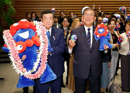 　関西万博の公式マスコットキャラクター「ミャクミャク」の人形と記念写真に納まる石破首相（右）と伊東万博相＝１４日夜、首相官邸