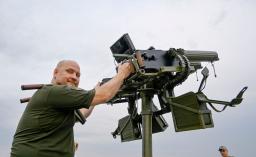 　機関銃を構えるビタリー・ズイエフさん＝７月、キーウ（共同）