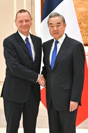 　握手するフランスのボンヌ大統領外交補佐官（左）と中国の王毅外相＝１５日、中国浙江省杭州市（新華社＝共同）