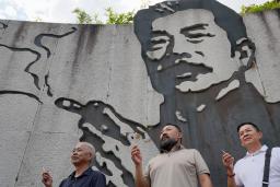 　魯迅の壁画前でたばこを手に記念撮影をする人たち＝９月、中国浙江省紹興市（共同）