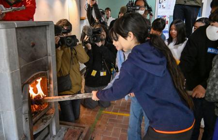 　石造りのまきストーブに火をともす神戸市立六甲山小の児童ら＝２３日午前