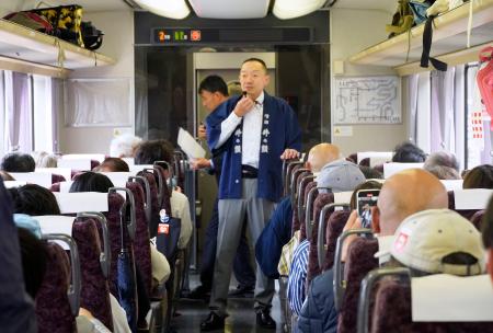 長野県内のJR飯田線を走る特別列車で、乗客に伊那地域の酒について説明する地元の酒造関係者=25日午後