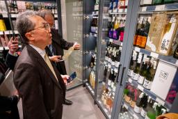 　ウクライナ・キーウのスーパーに陳列された日本酒を見る日本の代表団のメンバー＝２８日（共同）