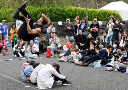 「大道芸ワールドカップin静岡2025」で、座った子どもたちの上を宙返りで飛び越えるアーティスト=31日午後、静岡市