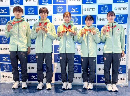 　トランポリンの世界選手権から帰国し、メダルを手に撮影に応じる宮野隼人（左から２人目）、田中沙季（同４人目）ら＝１１日、羽田空港