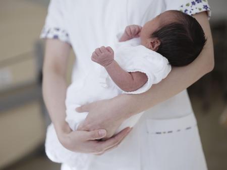 　病院で助産師に抱かれる新生児
