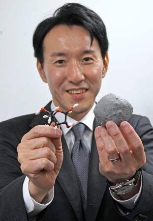 　小惑星ベンヌ（右）とリボースの模型を手にする東北大の古川善博准教授＝１日、東京都千代田区