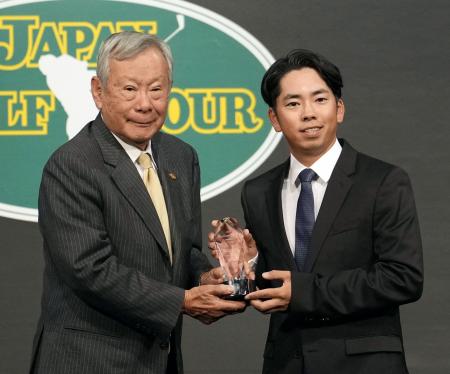 　日本ゴルフツアー機構の諸星裕会長（左）から、オールアラウンドランキング賞のトロフィーを受け取る生源寺龍憲＝８日、東京都港区